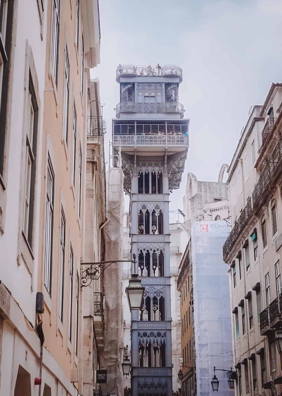 a narrow street of old buildings with the Santa Justa lift in the middle