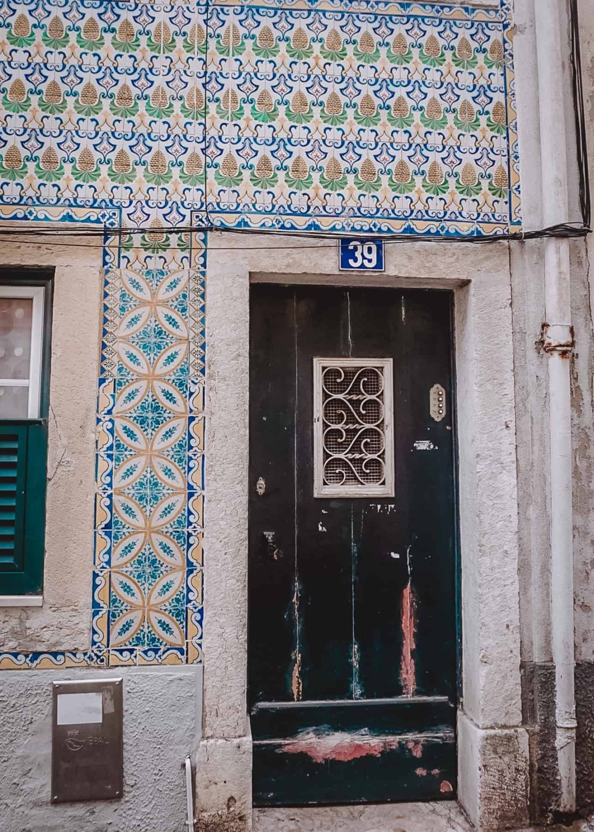 worn doorway with peeling paint surrounded by colourful tiled walls
