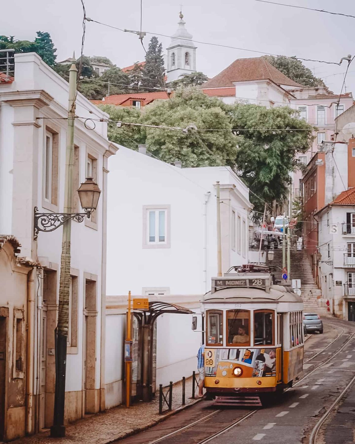 The famous Tram 28 moving in between a narrow street in the neighbourhood