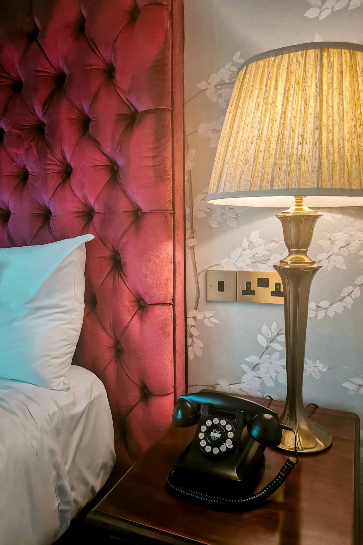 Close-up of a velvet headboard, bedside lamp and vintage telephone in a beautifully designed room at Cahernane House Hotel.