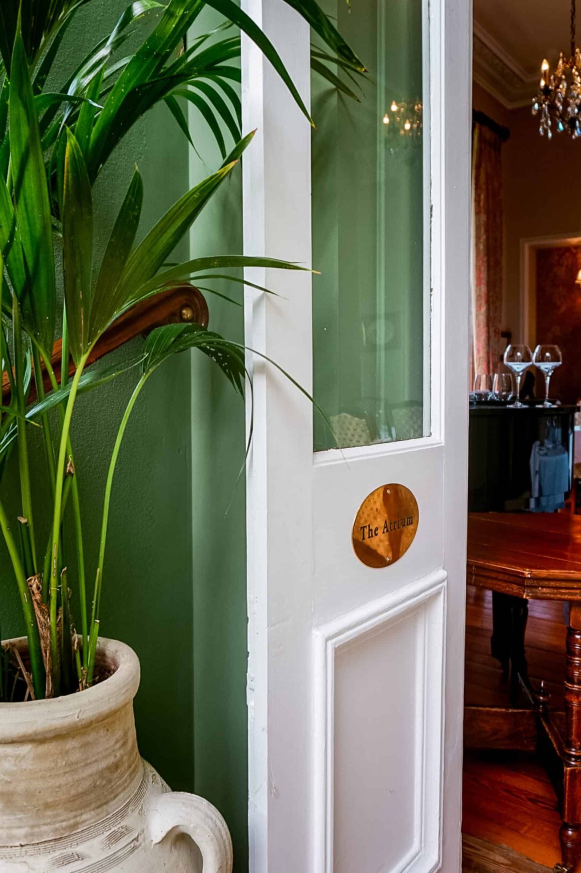 Doorway leading into The Atrium dining space at Cahernane House Hotel with elegant dรฉcor and indoor greenery.