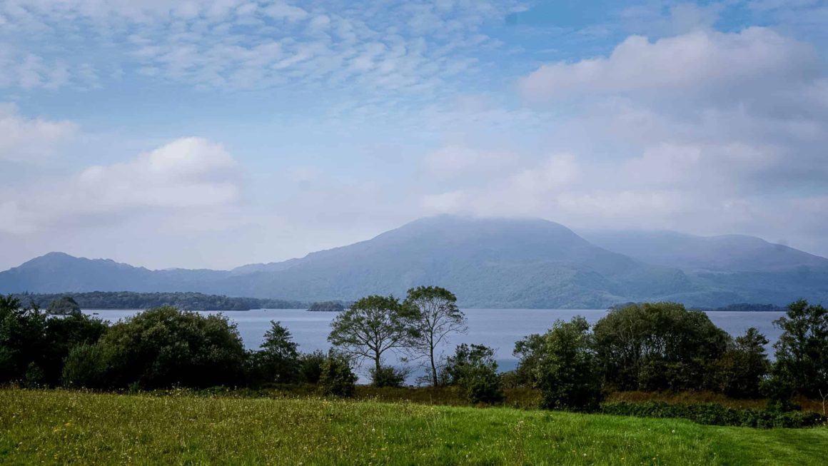 Rolling green lawns with lake and mountain views surrounding Cahernane House Hotel on the edge of Killarney National Park.