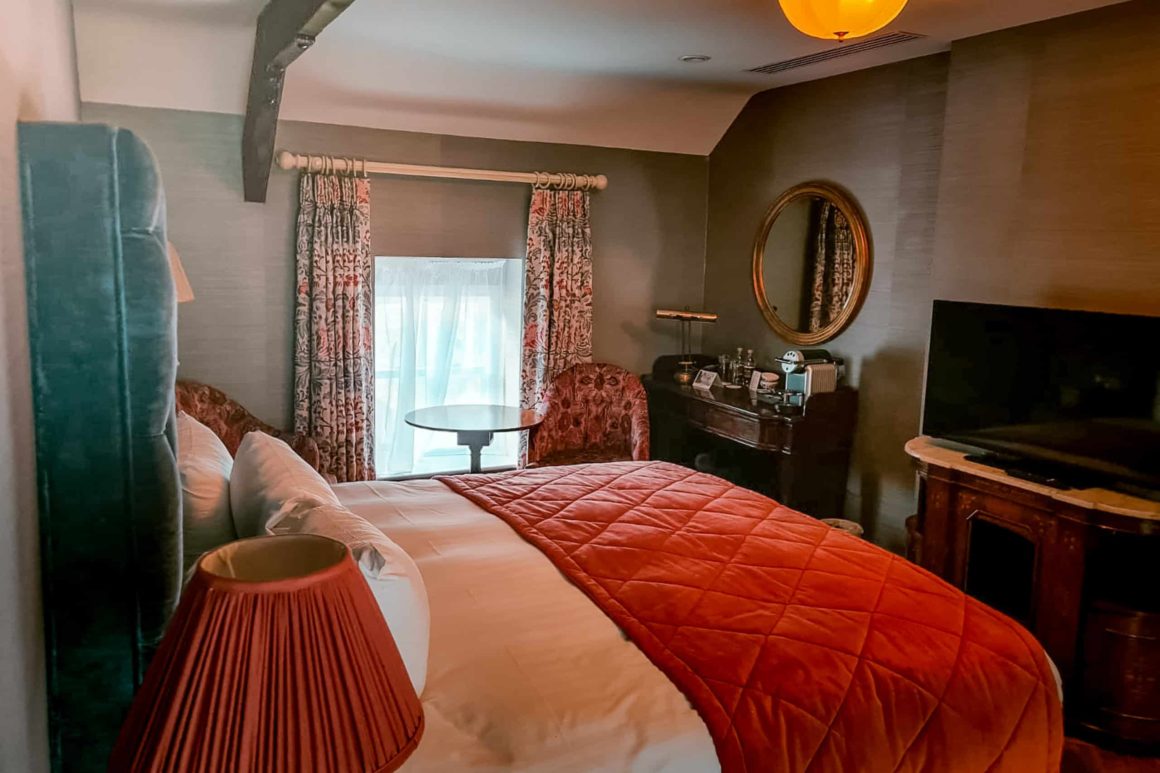 Stylish guest bedroom with plush furnishings, seating area and modern amenities inside a luxury country house hotel.