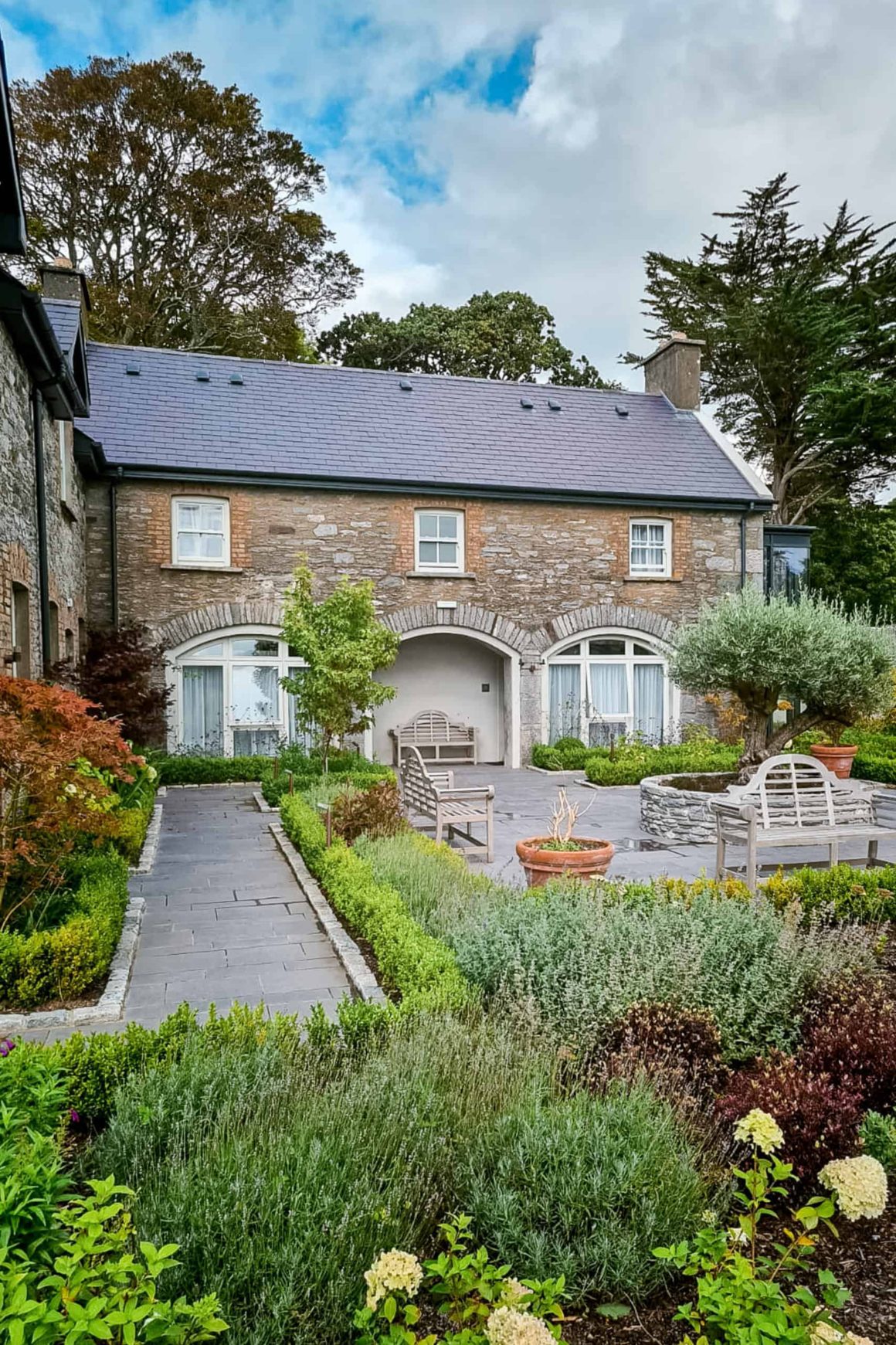 Landscaped courtyard with stone buildings, benches and manicured gardens creating a peaceful retreat for guests.