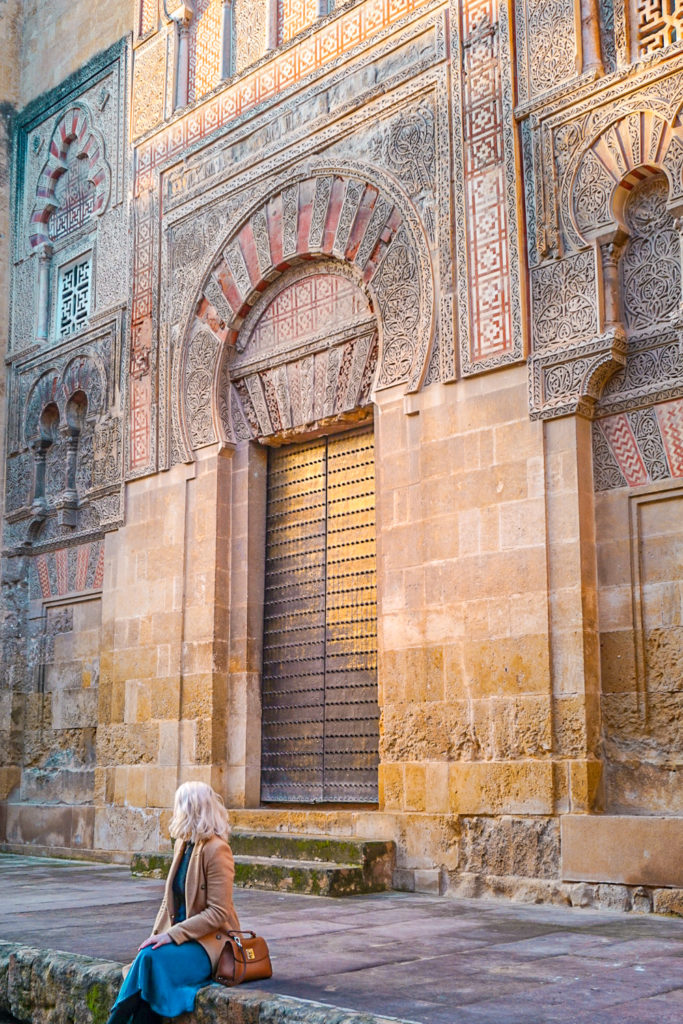 Blonde woman sits outside one of the doors of Cordoba's Mosque Cathedral