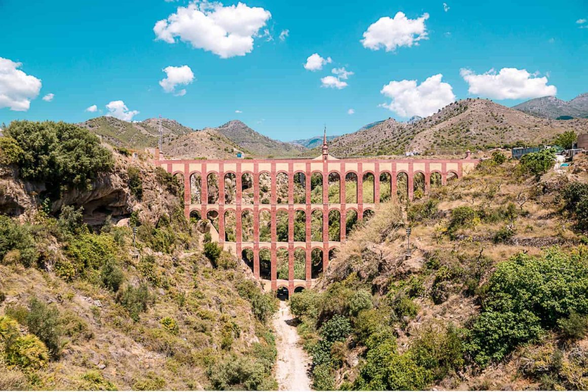 Historic multi-level Eagle Aqueduct spanning a rocky valley surrounded by hills near Nerja in southern Spain.