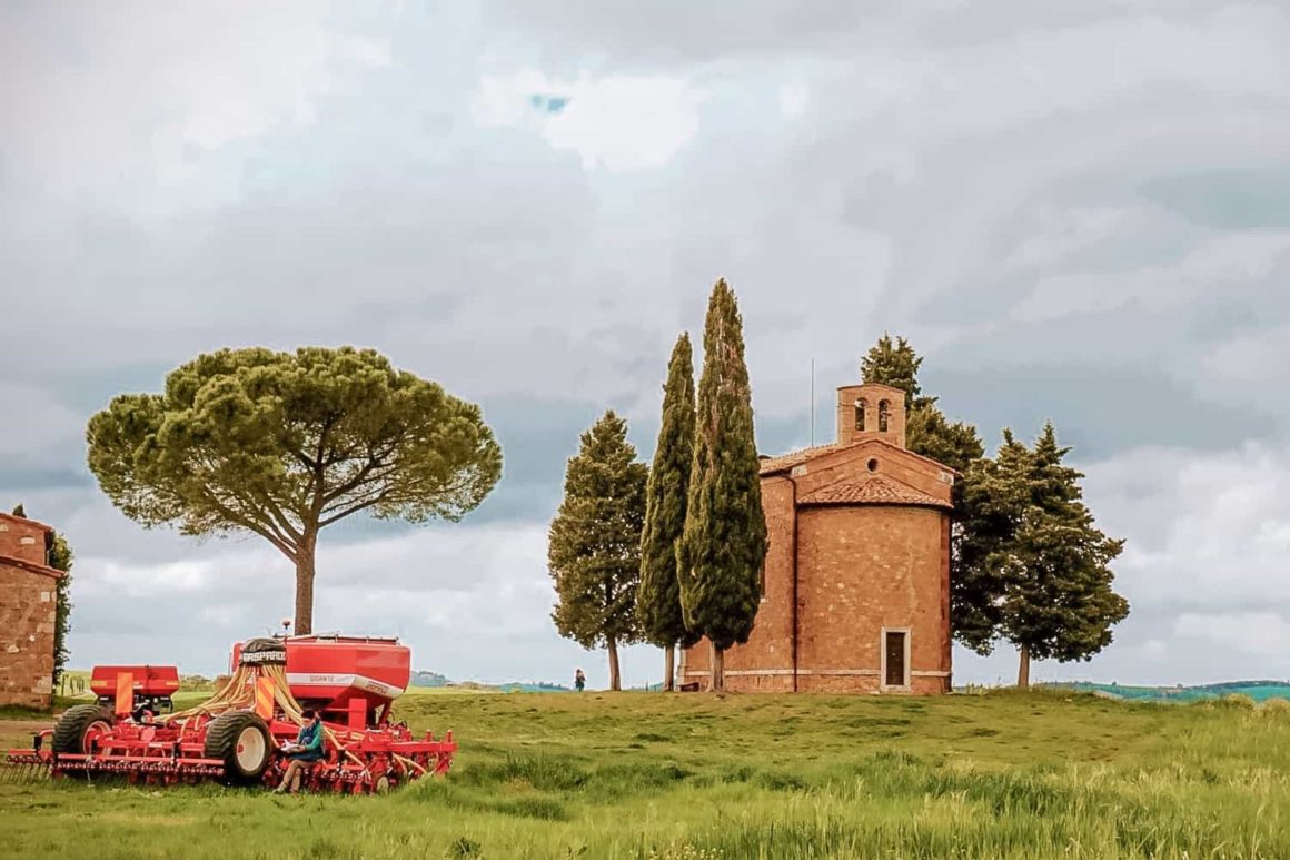 Historic brick chapel surrounded by cypress trees and farmland near Pienza in Tuscany
