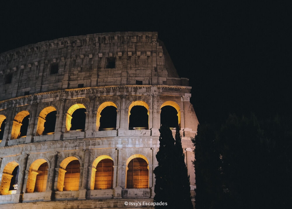 Pizza modena with thin slices of meat on a black table with cutlery rolled in a tissue on the side.