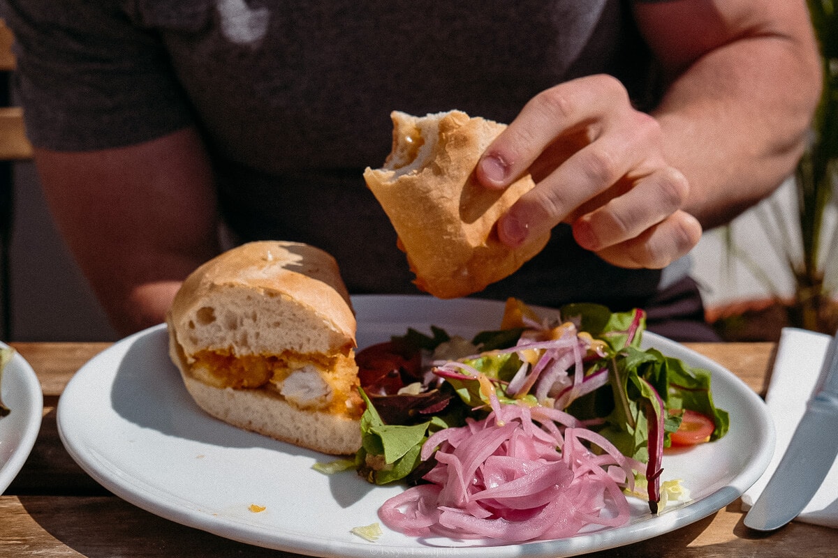 handing holding fish finger sandwich at mitchells seafood restaurant in clifden