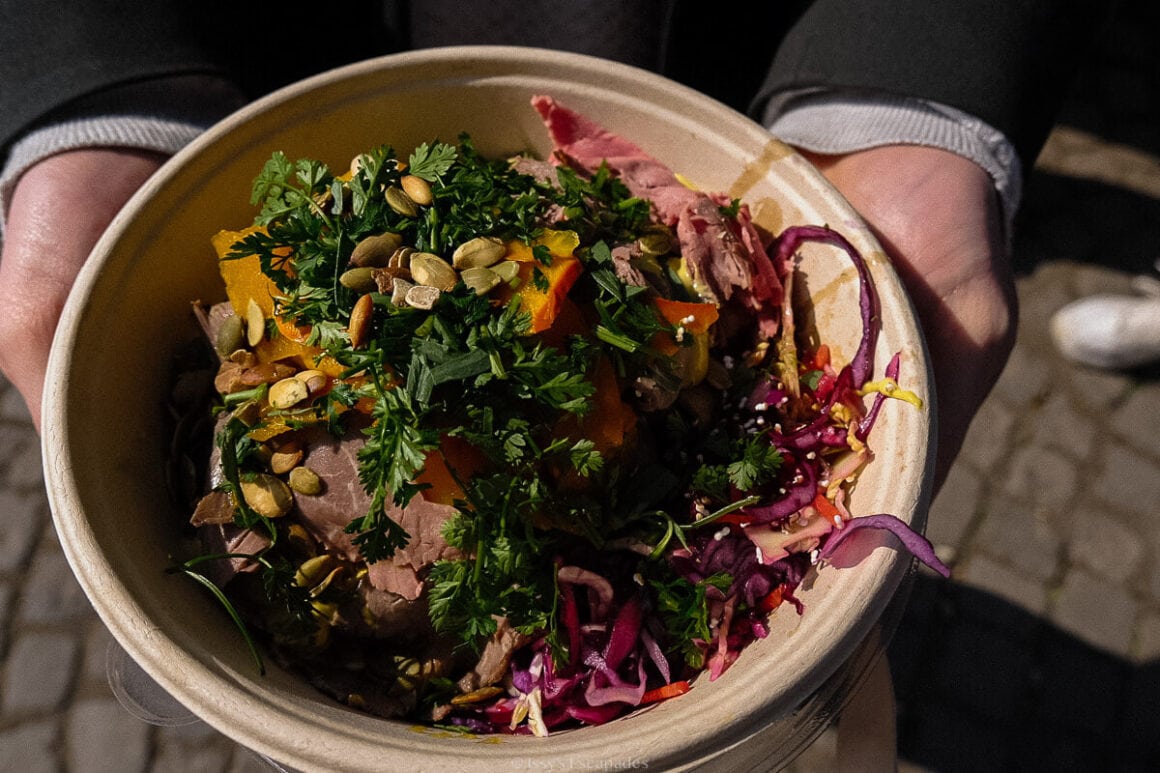 Bowl filled with colourful vegetables, herbs, seeds and other fresh ingredients at a Munich food market.