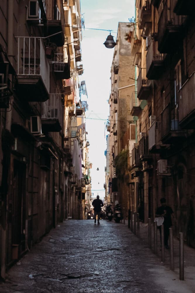 man walks down narrow cobbled street with overhanging buildings