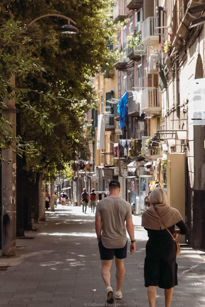 man and woman walk down street in naples
