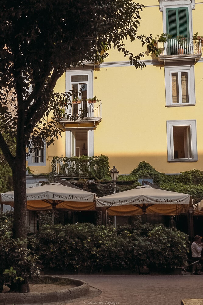 umbrellas in front of yellow buildings in naples piazza bellini