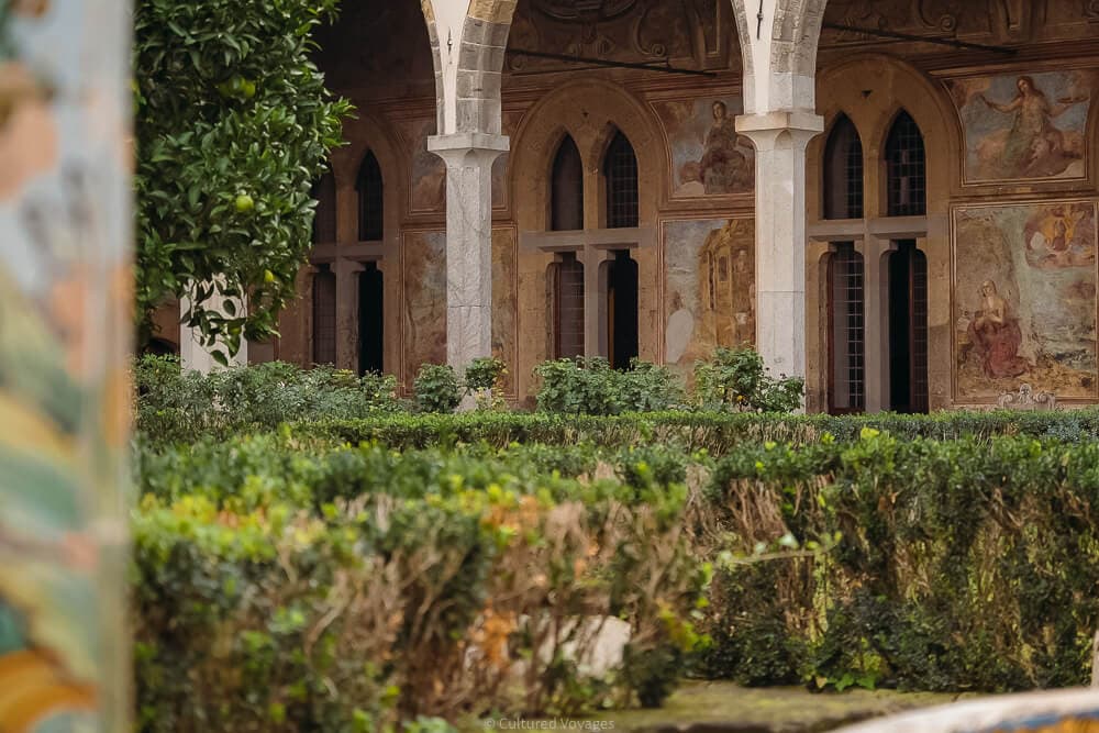 santa clara cloisters in naples, with view over rose bush through to frescoes