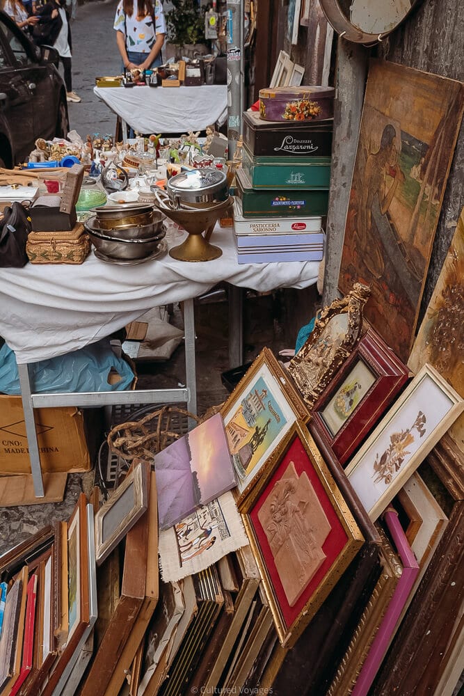 books and paintings lean against wall at street stall in naples historical centre