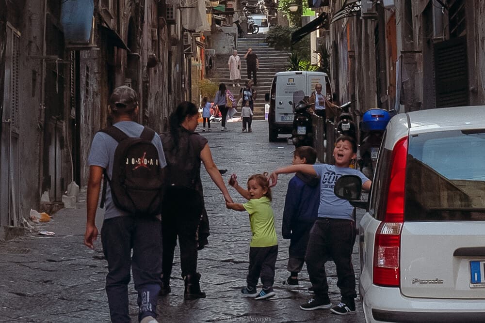 excited children turn and shout to someone on the street in spanish quarter naples