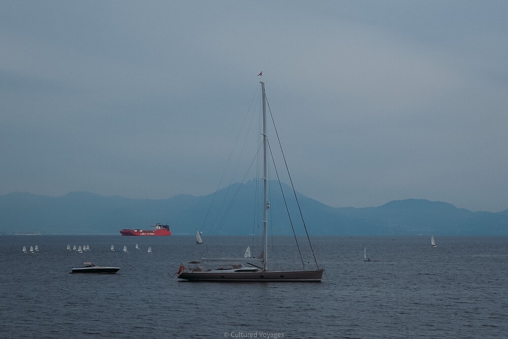 saling boat on blue waters of bay of naples with sorrento peninsula in background