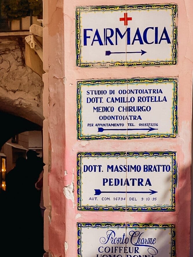 classic signs in white tile and blue handwritten font on pink wall in capri town