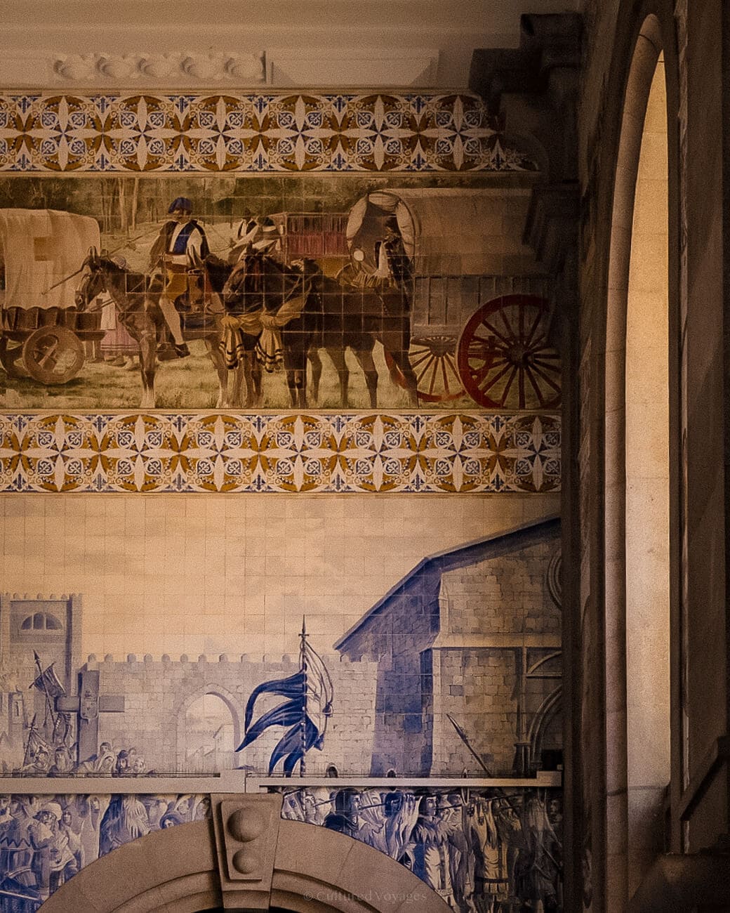 a tiled wall with murals of horses, carriages, people, and medieval
