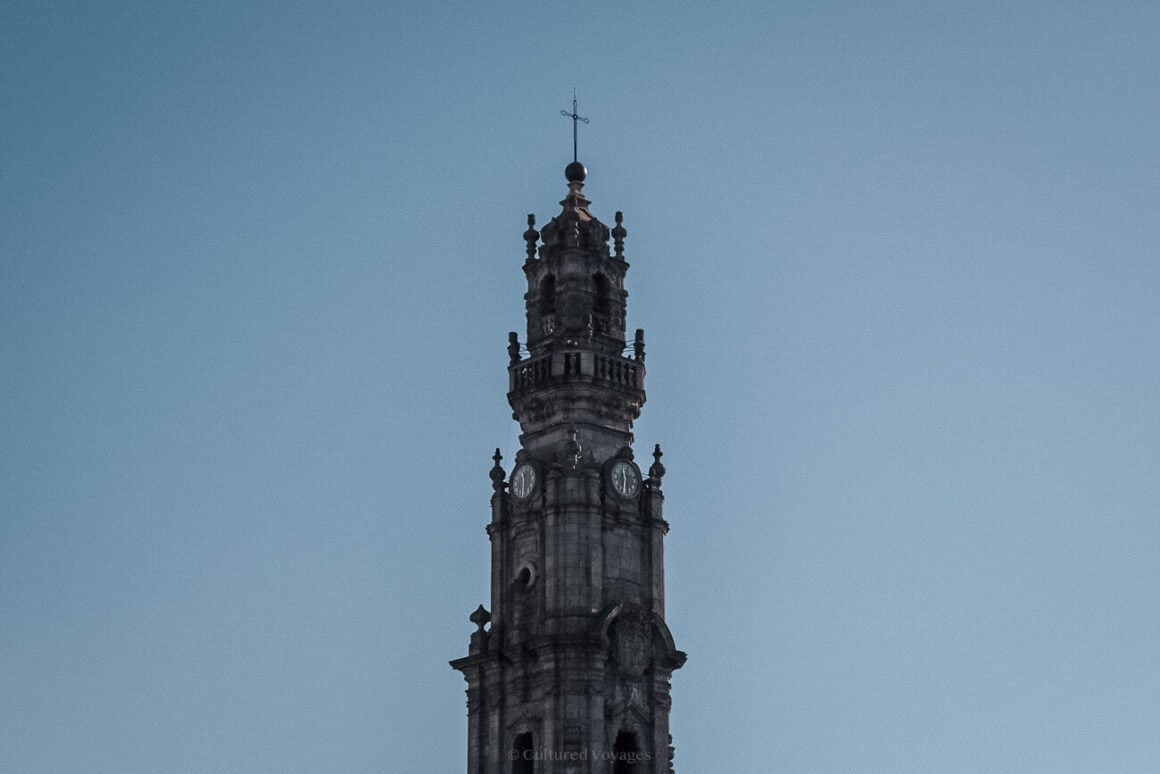 the clocks and cross on top of the Clerigos Tower with blue skies in the background - porto 1 day itinerary