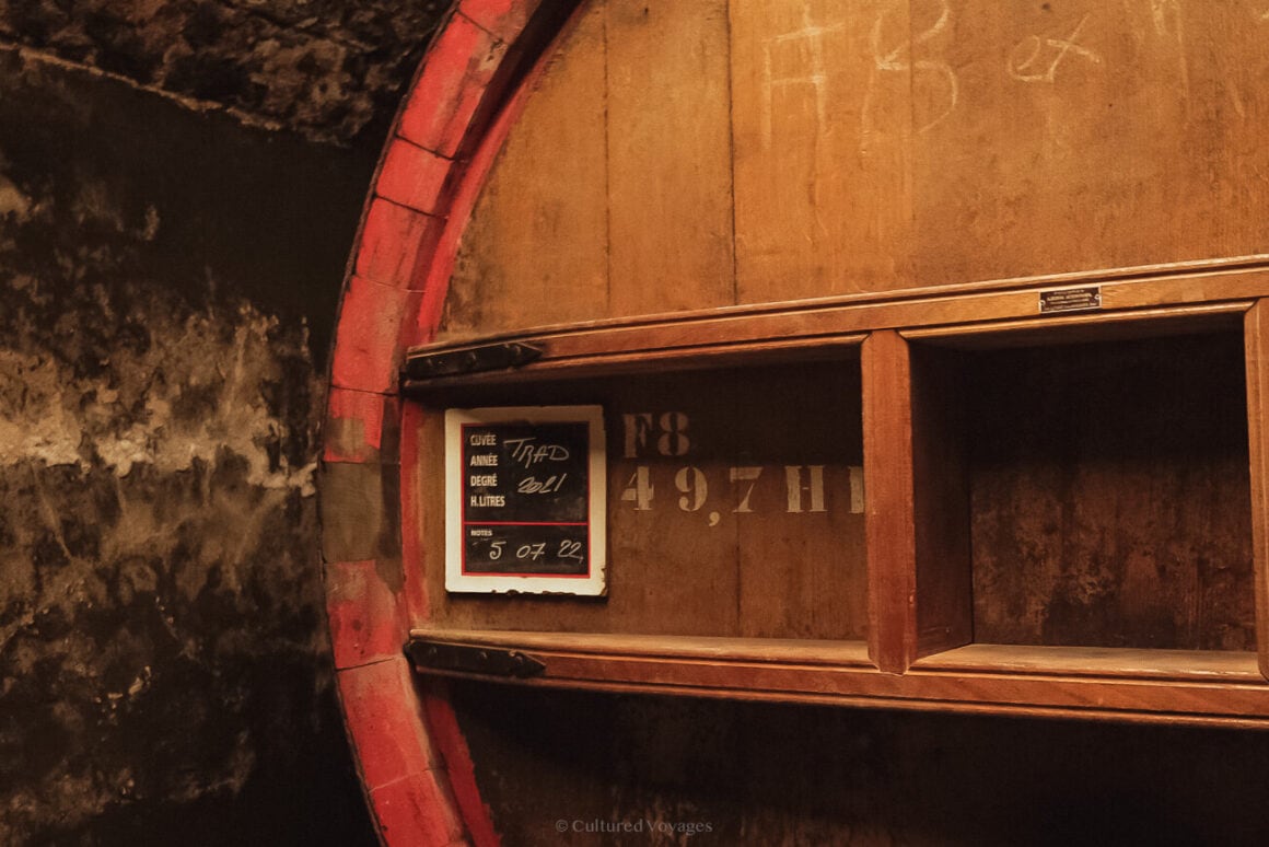 A close up of one side of a big wine barrel with a number in white paint and a label