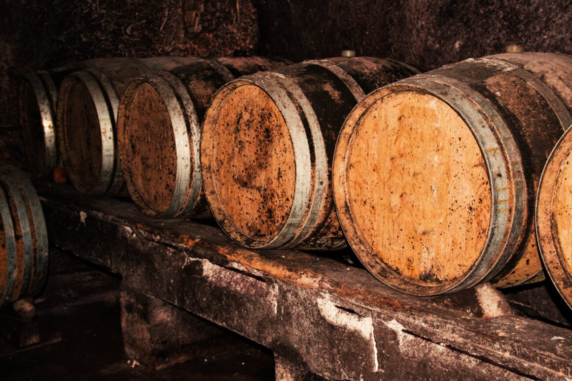 stacked wine barrels in a dark wine cellar to see in one of the Sorrento wine tasting tours.