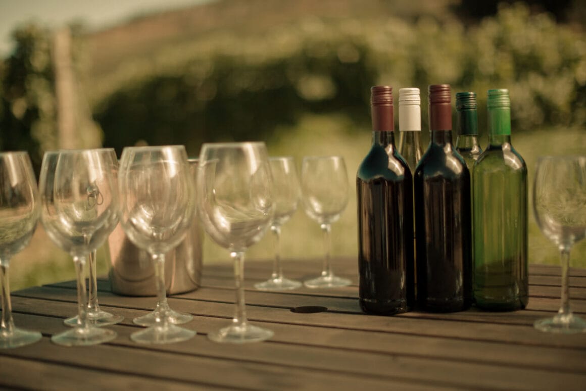 Five wine bottles and a couple of wine glasses on a wooden table for a Sorrento wine tasting experience