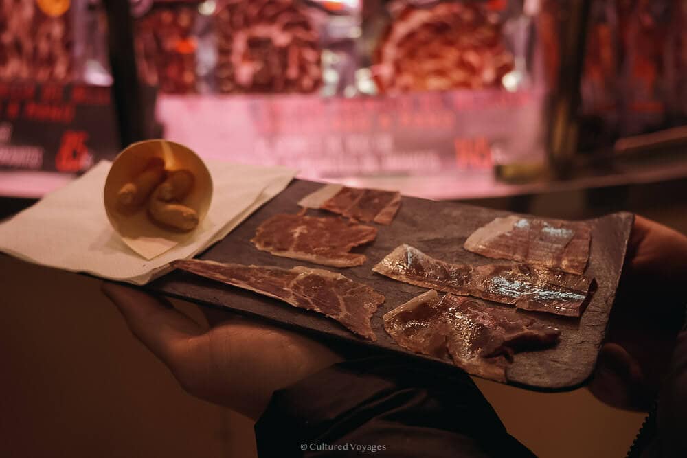 Slices of tapa on a wooden board served with a side of churros during one of the food tours in seville