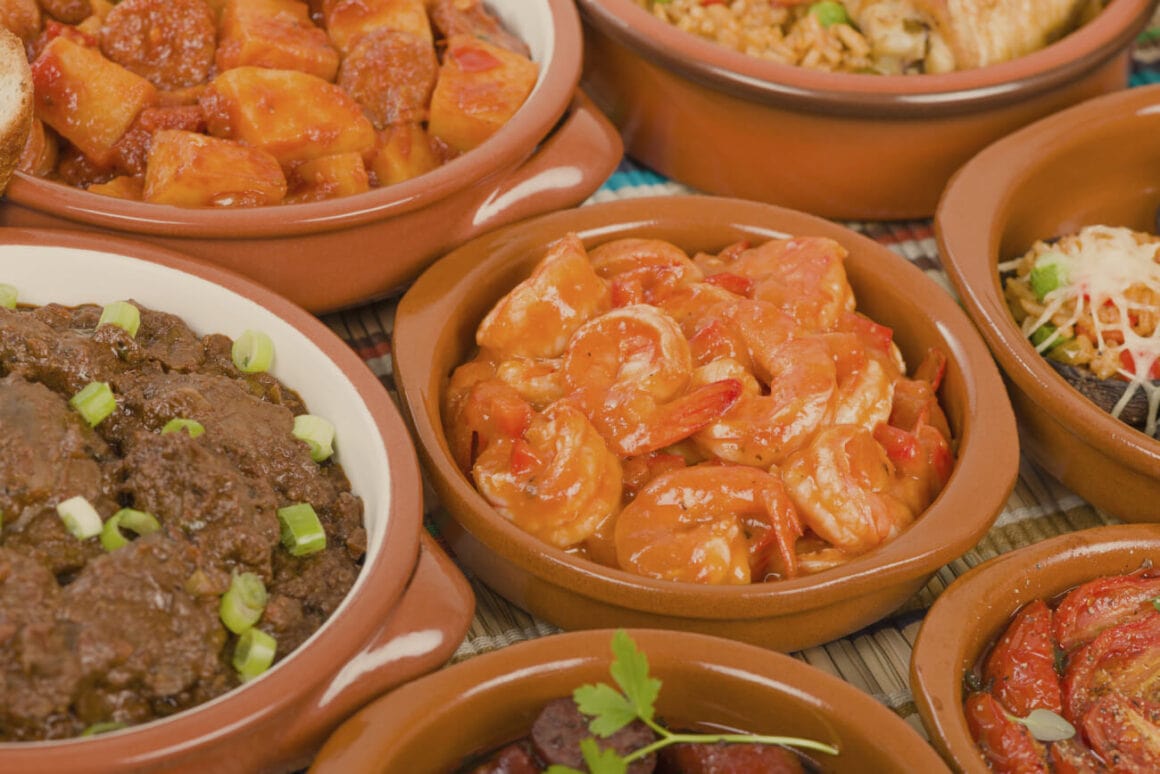 Shiny clay pots of tapas, shrimps, and vegetable dishes during a seville bike and tapas food tour