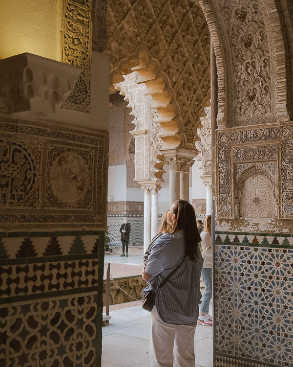 A person passing through an arched doorway filled decorated by colourful tiles.