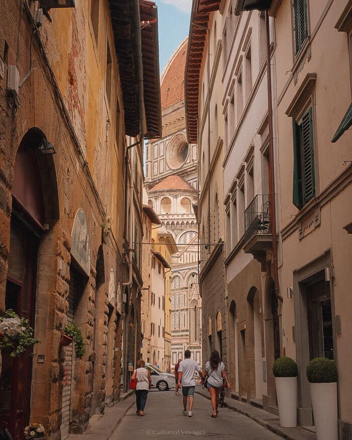 Florence Cathedral framed by the warm stone buildings of a narrow city street.