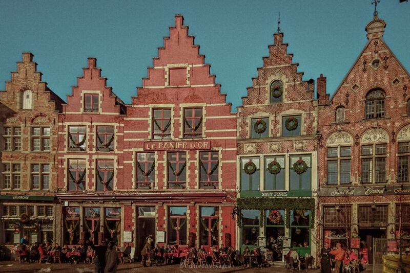 Stepped-gable buildings decorated with Christmas wreaths above cafés on the Markt in Bruges