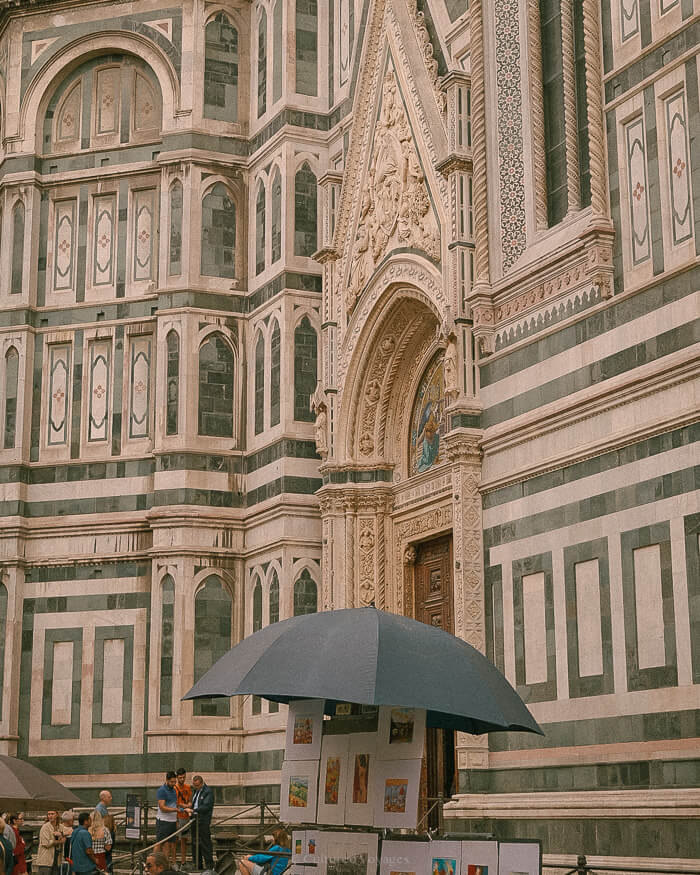 The facade of Santa Maria del Fiore, richly adorned with green patterns of rectangles and lines, showcasing intricate decorative elements and detailed craftsmanship.