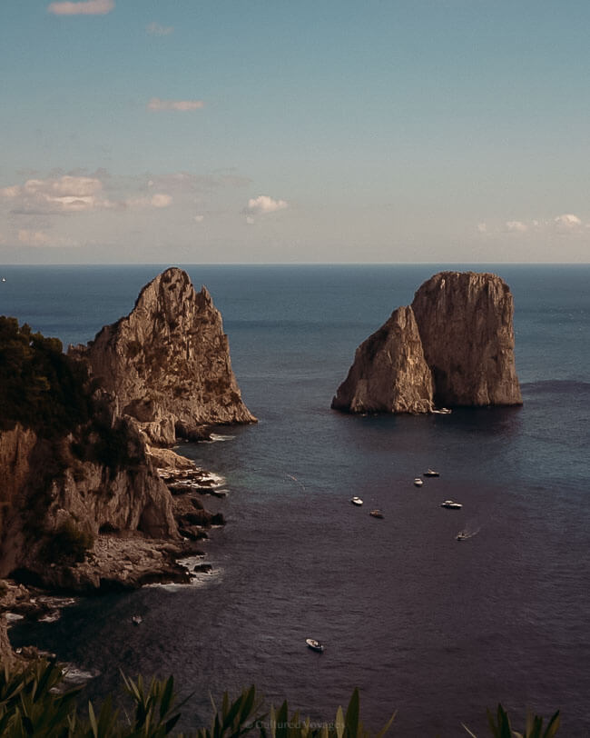 The iconic Faraglioni rock formations rising from the sea, surrounded by boats and cliffs, captured during a Naples to Capri Day Trip.
