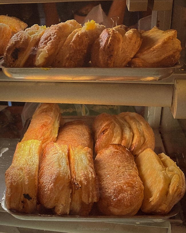 Trays of freshly baked pastries with golden, flaky layers displayed in a local bakery on Procida Island, Italy, creating a mouthwatering scene.