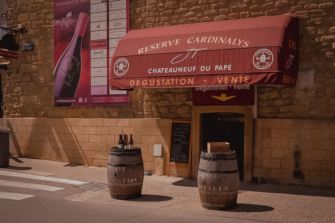Wine-tasting cellar with a red awning and wine barrels outside in Châteauneuf-du-Pape.