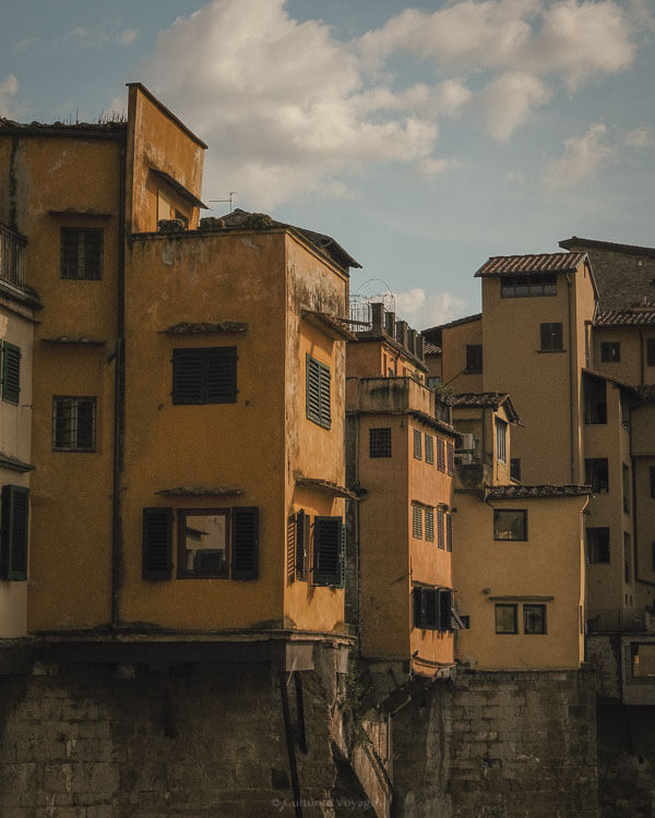 Close-up of the sunlit, weathered homes built on Ponte Vecchio, with warm textures under late afternoon skies.