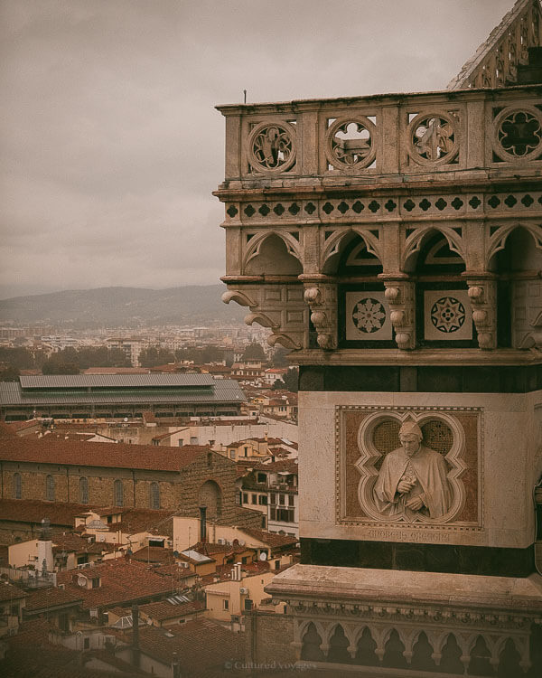 Close-up of Giottoโs Bell Tower sculpture detail overlooking Florence rooftops and distant hills, captured during the best time to visit Florence.