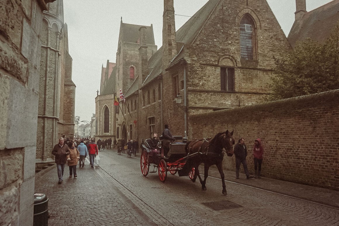 Visitors stroll along cobbled streets as a horse-drawn carriage passes by medieval buildings in Bruges, capturing the old-world charm that makes it one of the best European cities to visit in winter.