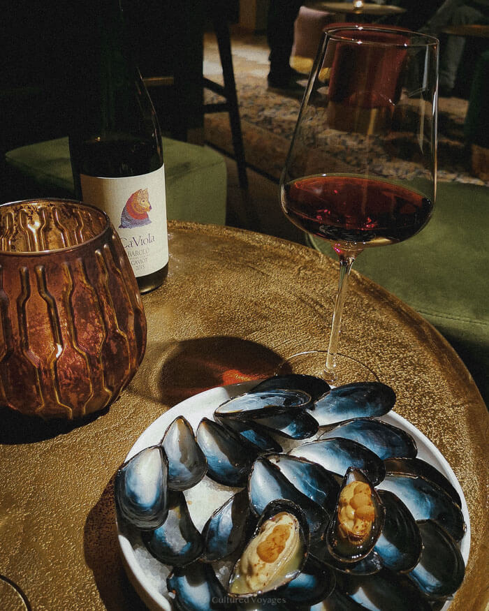 A plate of fresh mussels paired with a glass of red wine on a candlelit table, capturing the cosy culinary charm of one of the best European cities to visit in winter.