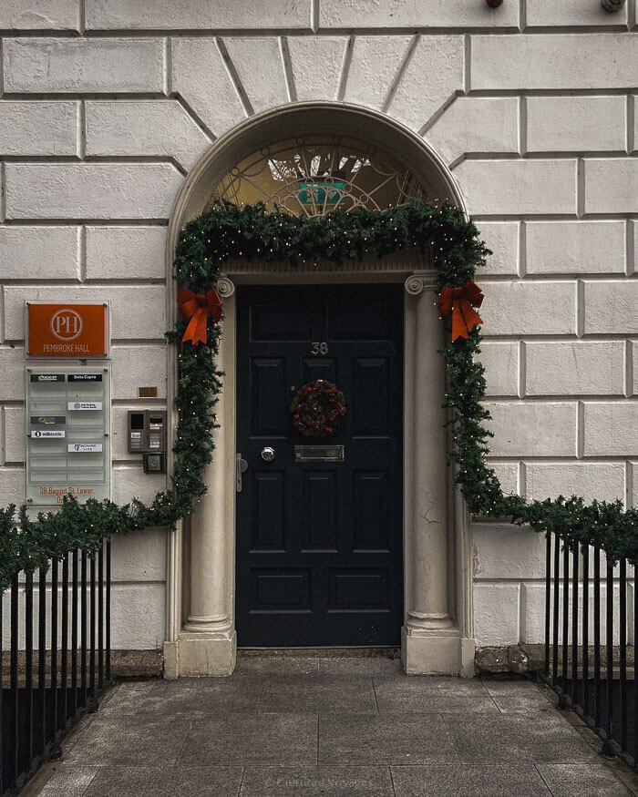 A grand Georgian doorway adorned with festive wreaths and greenery, adding holiday charm to a Dublin street.