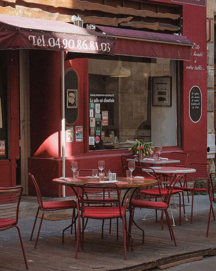 An inviting café terrace with red chairs and neatly set tables on a quiet European street, showcasing the charm of one of the best European cities to visit in winter.