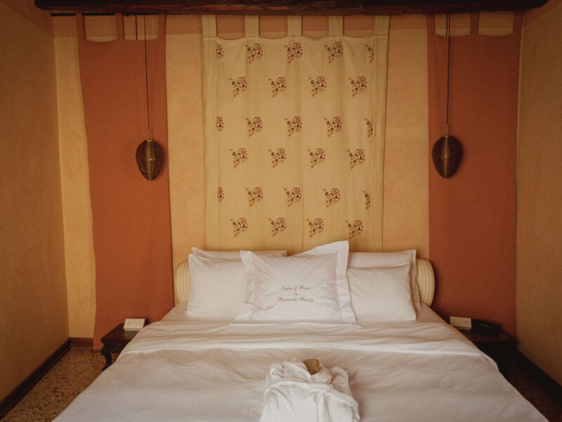 White bed linen and embroidered cushions in a Venetian bedroom.