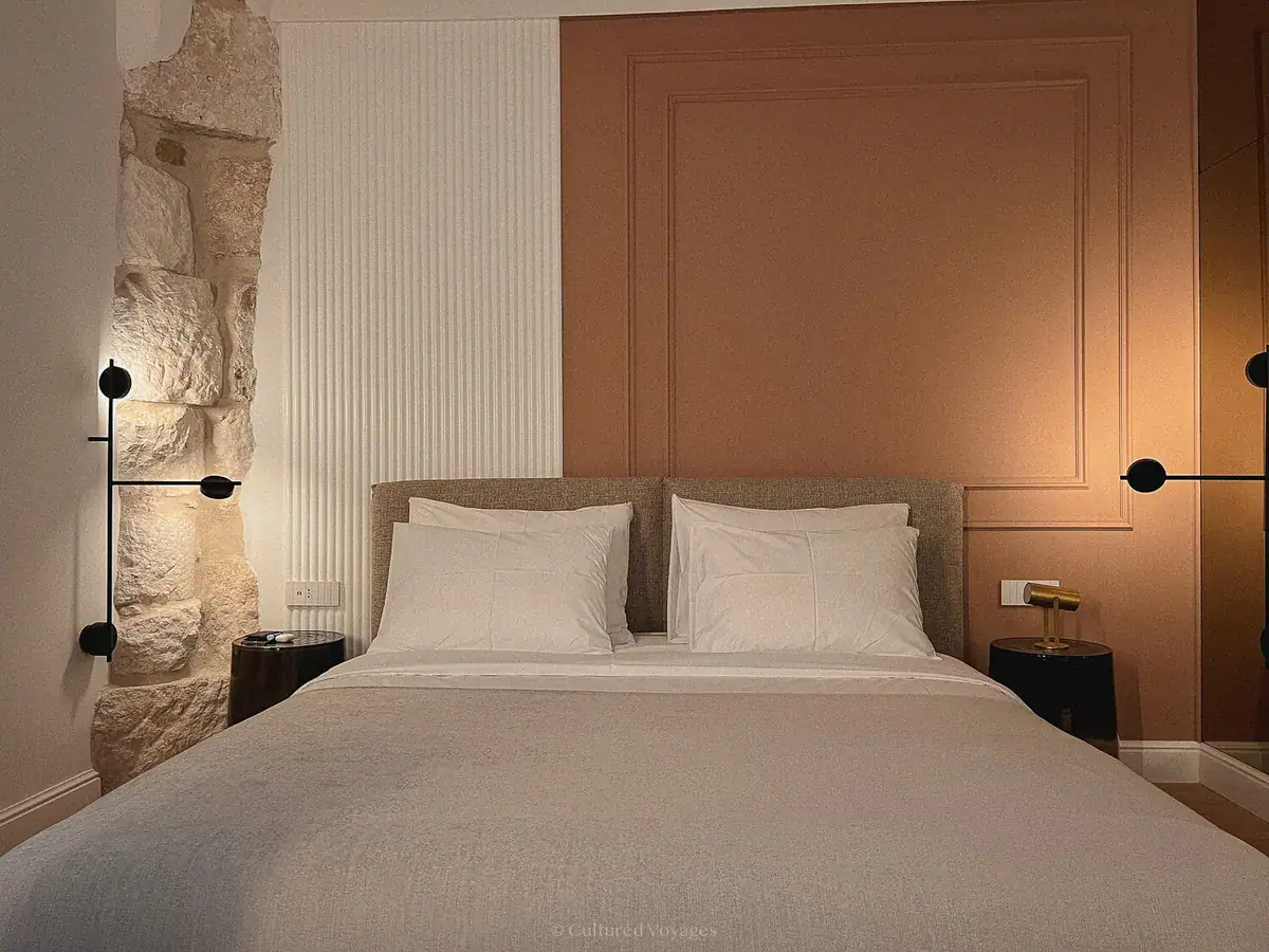 Double bed beside exposed stonework and a terracotta panel in a guest room in Split, Croatia.