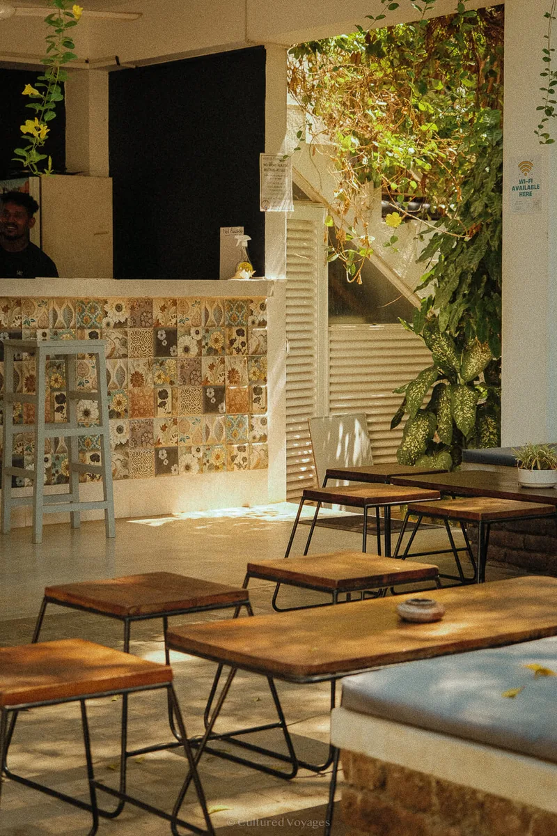 Tiled reception counter and low seating beneath greenery at Salt House in Hiriketiya, Sri Lanka.