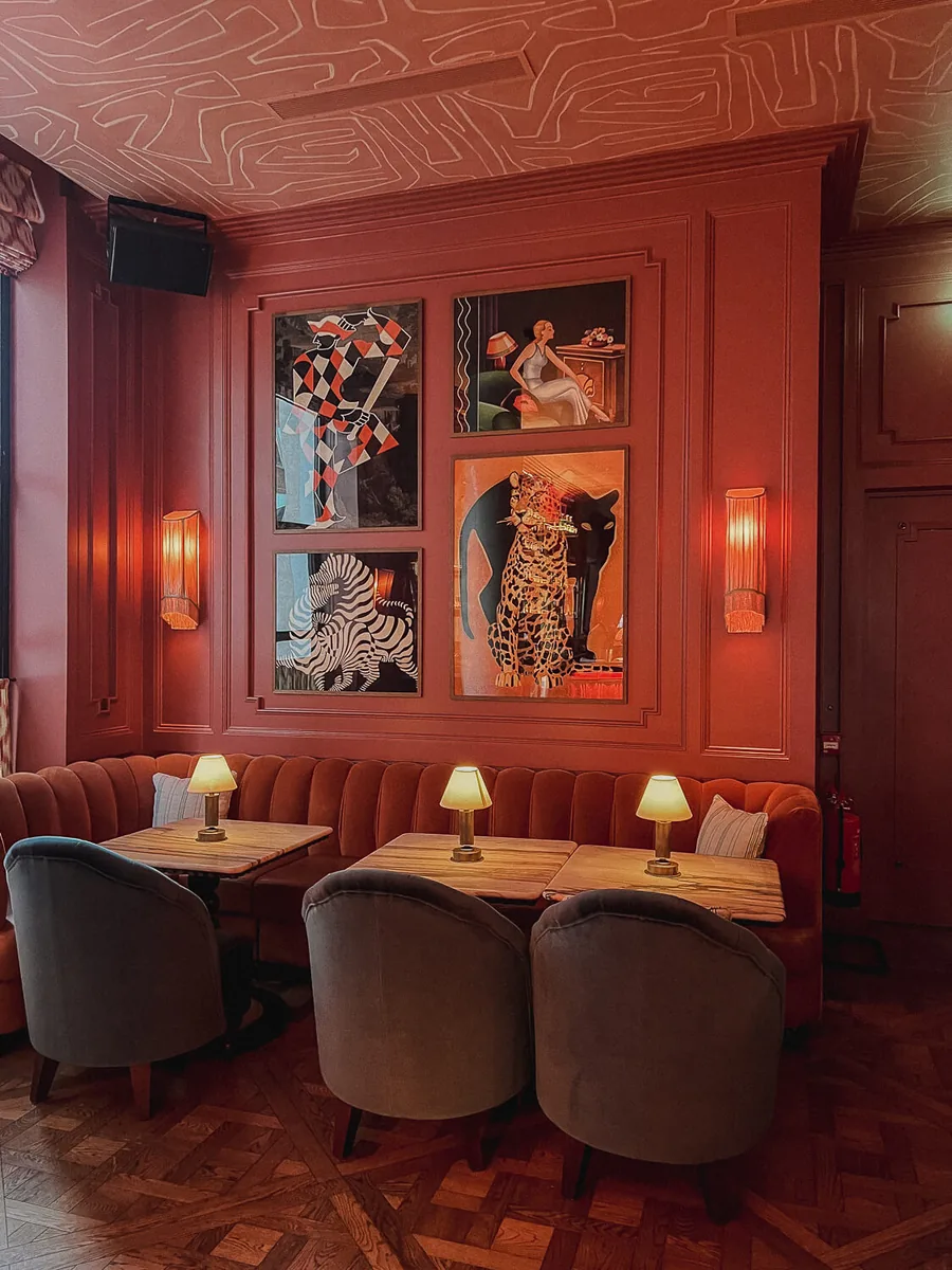 Red-panelled bar seating at The Leinster in Dublin, with framed art and lamp-lit tables.