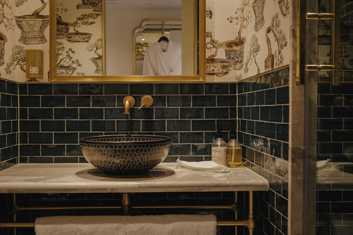 Black-tiled bathroom at The Leinster in Dublin, with a patterned basin and brass taps.