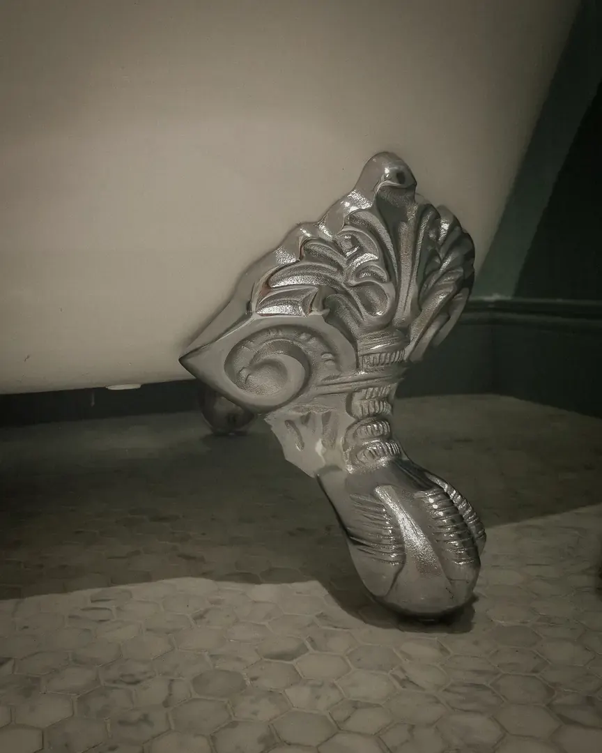 Silver claw foot of a freestanding bath on marble hexagon tiles