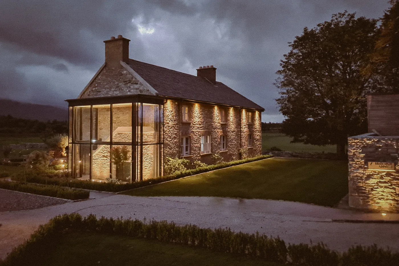 The Coach House at dusk, its glass extension lit from within