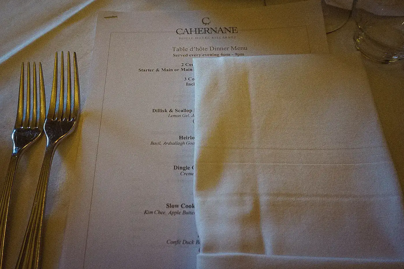 Dinner place setting with silver forks, a folded napkin and the Cahernane House menu